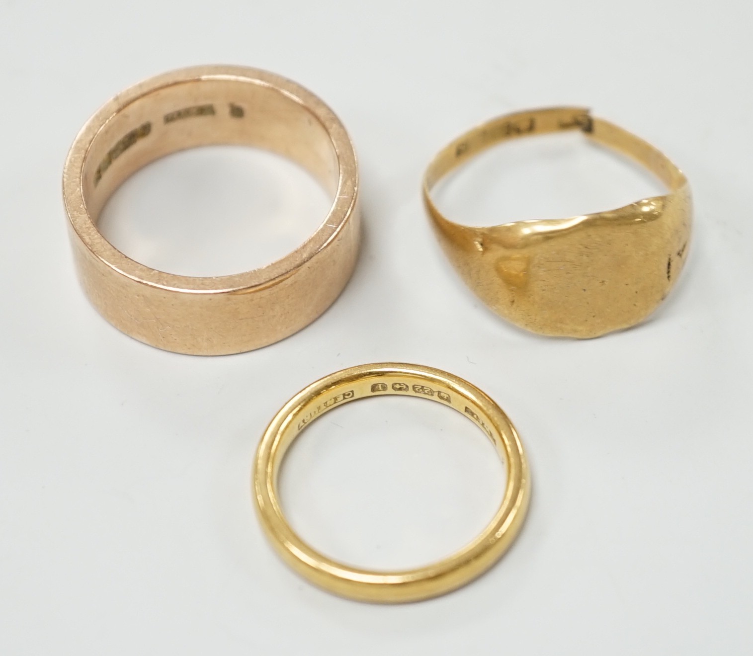 A 1930's 22ct gold wedding band, size K, 4.1 grams, a 9ct gold wedding band, size Q, 9.3 grams and a broken 18ct gold signet ring, 2.9 grams.